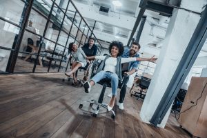 Man pushing woman sitting in an office chair.