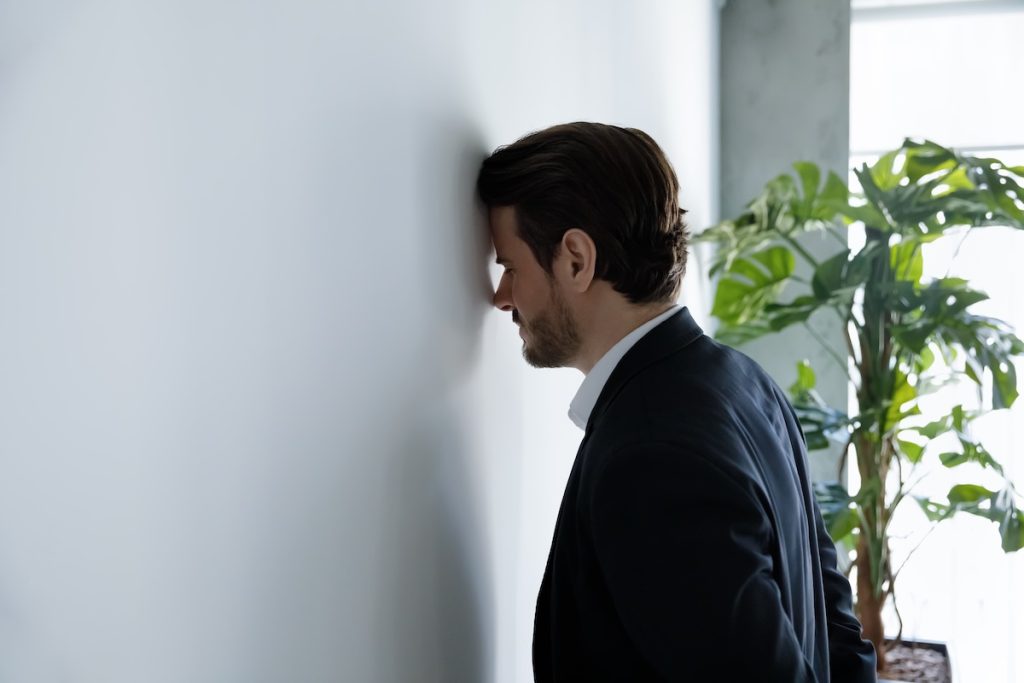 Man banging his head against a wall.